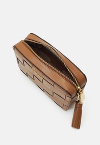 Sac rectangulaire en cuir marron avec un design tissé, fermeture éclair dorée et accent en gland. La fermeture éclair ouverte révèle un compartiment intérieur.