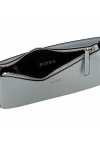 Borsa a mano in pelle grigia con chiusura a zip, caratterizzata da un logo dorato, una texture liscia e un interno nero.