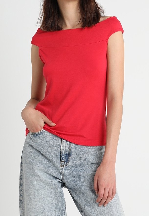 Red off-the-shoulder top with a straight neckline, paired with high-waisted light blue denim jeans. Smooth fabric with a fitted design.