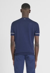 Maglione a maniche corte di colore blu navy con scollo rotondo e bordo bianco a contrasto sulle maniche. Texture liscia, design aderente.