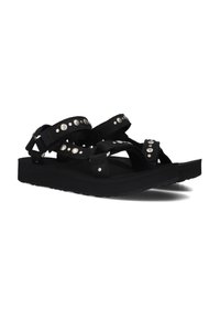Zwarte sandalen met verstelbare banden, metalen studs, een platte zool en een textuur voetbed. Ontworpen voor comfort en duurzaamheid.