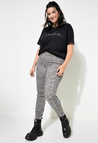 T-shirt nera con la scritta "London", abbinata a jeans grigi a fantasia con un design sottile. Stivaletti neri con suola spessa.