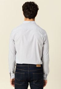 Lichtblauw overhemdd met een klein geometrisch patroon, voorzien van een spread collar en lange mouwen, gedragen met donkerdenim jeans.