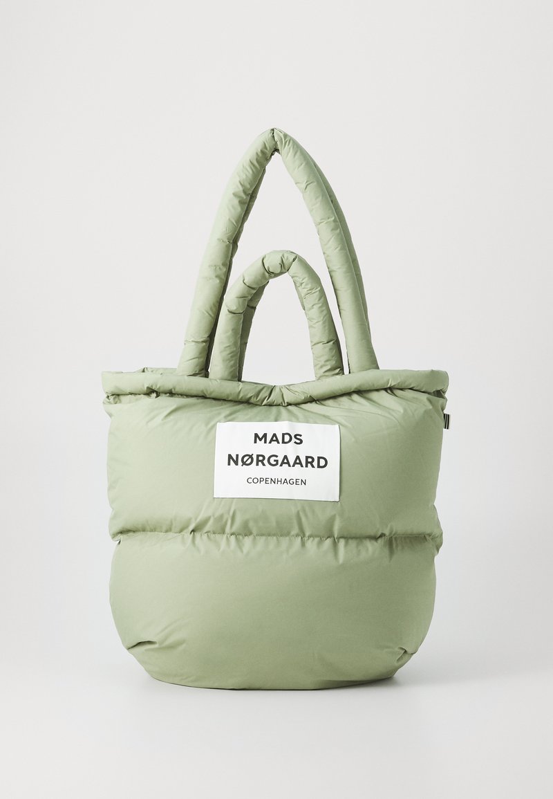 Sac fourre-tout rembourré de couleur vert clair, avec deux poignées en boucle et une étiquette sur le devant portant la mention "MADS NØRGAARD COPENHAGUE" en texte noir.