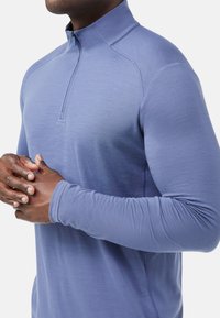 Pullover a maniche lunghe con zip a quarto in azzurro chiaro. Presenta un'accenno testurizzato sulla spalla e un tessuto liscio e elastico per il comfort.