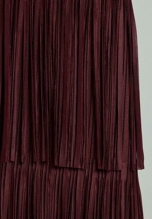 Burgunderroter Stoff mit Fransen, der vertikale Streifen mit einer glatten Textur aufweist, mit einem geschichteten Design, das ein fließendes Aussehen verleiht.