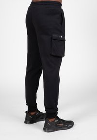 Zwarte joggingbroek van katoenmix, met zijzakken, geribbelde boorden en een logopatch op de cargozak.