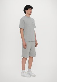 Grå bomull t-skjorte og shorts, avslappet passform, med rund hals og søm på bunnen. Brukt med hvite sneakers og ankelsokker.