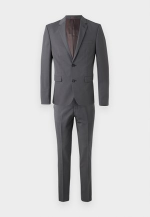 Traje gris a medida que incluye una chaqueta de dos botones con solapa en forma de muesca y pantalones de frente plano, confeccionado en una tela suave para un acabado elegante.
