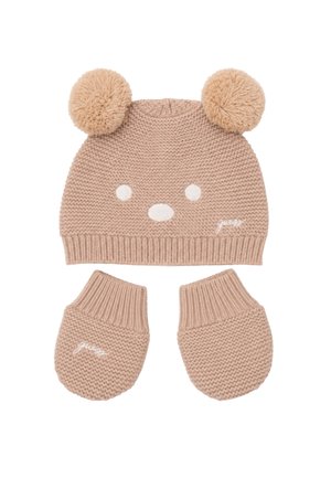 Bonnet de bébé beige tricoté avec deux pompons et visage brodé, assorti à des moufles tricotées beiges assorties.