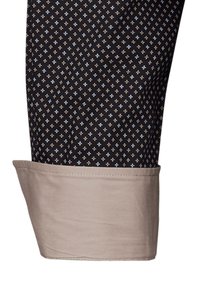 Colletto di camicia a maniche lunghe in tessuto nero con motivo a diamante in azzurro chiaro e beige. Il polsino beige evidenzia una trama liscia.