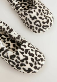 Lippikuvioiset tossut, jotka on valmistettu pehmeästä keinoturkismateriaalista. Pyöristetty toe ja liukuvat malli musta-valkoisella väriominaisuudella.