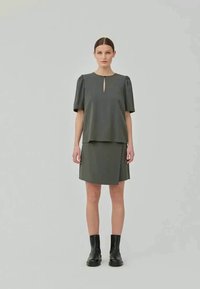 Conjunto de vestido verde oliva con una blusa de manga corta abullonada que presenta un escote en forma de llave y una falda a juego, todo confeccionado en una tela suave y texturizada.