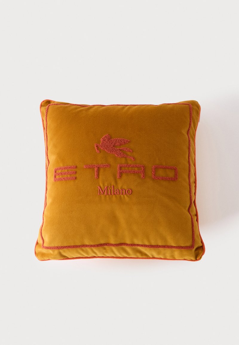 Coussin carré jaune moutarde avec bordure brodée rouge et les mots "ETRO Milano" ainsi qu'un logo de cheval ailé en fil rouge.