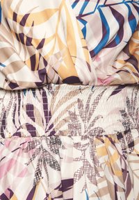 Kuvioitu mekko, jossa on kukkakuvio sinivioletin, beige ja sinisen sävyissä. Vyötärö on kootun näköinen, ja kangas on pehmeää ja laskeutuvaa.
