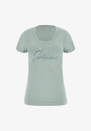 Camiseta de algodón verde claro con escote en pico. Presenta la palabra "Guess" en letras brillantes y el año "est. 1981" debajo. Mangas cortas.