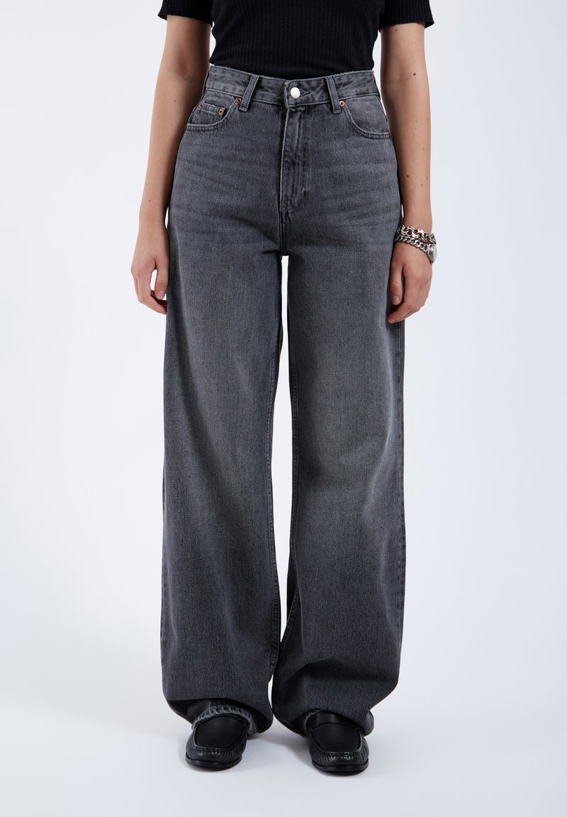 Weit geschnittene graue Denim-Jeans mit hoher Taille, einem einzelnen vorderen Knopf und standardmäßiger fünf Taschen-Design, mit einer leicht ausgewaschenen Textur.