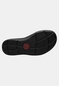 Suola di scarpa in gomma nera con superficie texture, caratterizzata da un accento rosso circolare contrassegnato "38" e un motivo di scanalature per una buona aderenza.