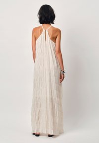 Maxikleid in Creme, mit geraffter Textur, Halterneck-Ausschnitt und einem Schlüsselloch-Detail im Rücken, fließender Silhouette und langem Design bis zum Knöchel.