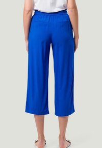 Modré culottes vyrobené z lehkého materiálu, s elastickým pasem a dvěma zadními kapsami, zkrácené těsně pod koleny.