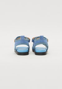 Blauwe sandalen van zacht materiaal, met open hielen, verstelbare banden en een gestructureerde zool. Lichtblauwe voetbed met een zwarte buitenzool.