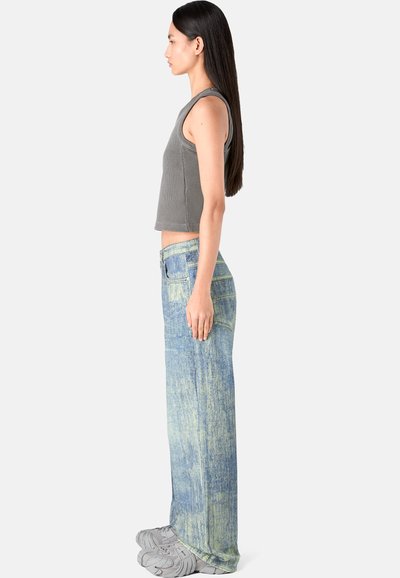 Harmaa ribatty crop-top, joka on yhdistetty vaaleansinisiin leveälahkeisiin farkkuihin, joissa on kulutettu viimeistely. Mallilla on päällään harmaat lenkkarit.