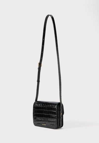 Μαύρη τσάντα ώμου από δέρμα με ανάγλυφη υφή κροκοδείλου, ρυθμιζόμενο λουράκι και μεταλλικά στοιχεία σε χρυσό τόνο σε λευκό φόντο.