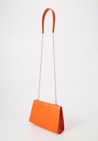 Borsa a mano in pelle arancione con forma strutturata, dotata di una tracolla a catena dorata rimovibile e una superficie liscia e strutturata.