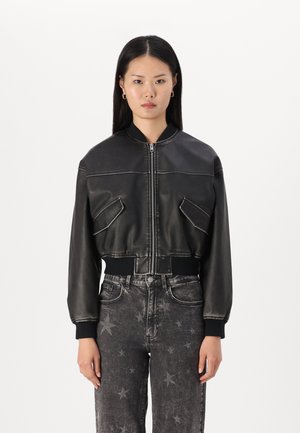 Giubbotto bomber in pelle nera con polsini e colletto a coste, dotato di due tasche frontali e cuciture a contrasto, abbinato a jeans scuri con motivo a stelle.