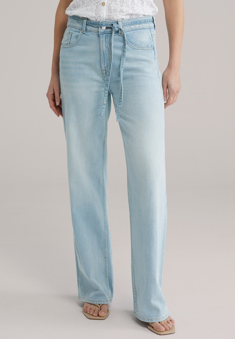 Jeans di denim blu chiaro a vita alta con vestibilità comoda, caratterizzati da un dettaglio con fiocco frontale e dal classico design a cinque tasche.