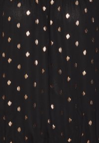 Tessuto nero con una texture trasparente, caratterizzato da pois metallici in oro di forme e dimensioni varie sparsi su tutta la superficie.