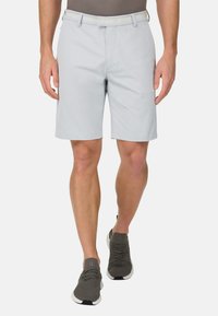 Hellgraue Shorts mit flacher Vorderseite, Gürtelschlaufen und Seitentaschen. Kombiniert mit dunkelgrauen Sportschuhen aus strukturiertem Material.