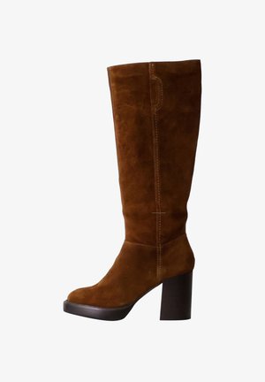 Botas de ante marrón hasta la rodilla con un chunky tacón negro, que presentan costuras contrastantes y una punta redondeada. Textura suave y diseño simple.