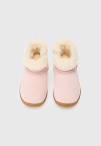Bottines en suède rose avec une doublure en fausse fourrure beige et une semelle en caoutchouc plate. Le design est simple avec un bout arrondi et une cheville retroussée.
