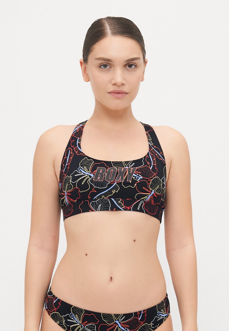 Black bikini top with floral pattern in red, yellow, and blue. Features a square neckline and thick straps, branded with "ROXY" in bold letters.