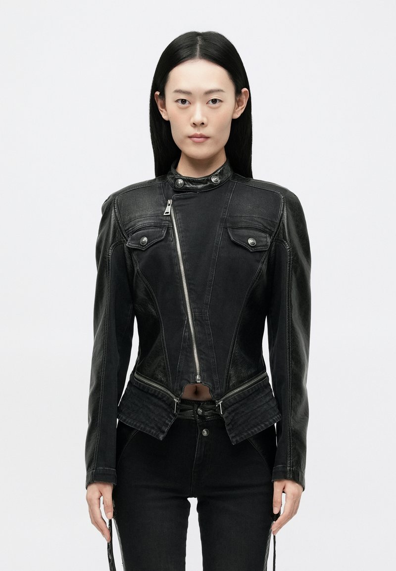 Must mustruudel nahkjakker, mis on sobiva disainiga, lukuga kinnitamine, kõrge krae ja kaks esikotti. Omab tekstuurilisi aktsente ja lühendatud hem.