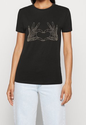 T-shirt noir avec un graphisme en contour blanc de deux mains formant un cœur, porté par une personne avec un jean bleu clair.