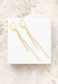 Guldfärgade droppörhängen med två tunna, förlängda kedjor—en slät och en med sfäriska accenter—fästa vid ett lås med hävstång.