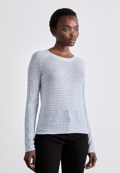Camisa de manga larga azul claro con un patrón texturizado, cuello redondo y diseño ajustado. Combinada con pantalones negros, mostrando un look casual.