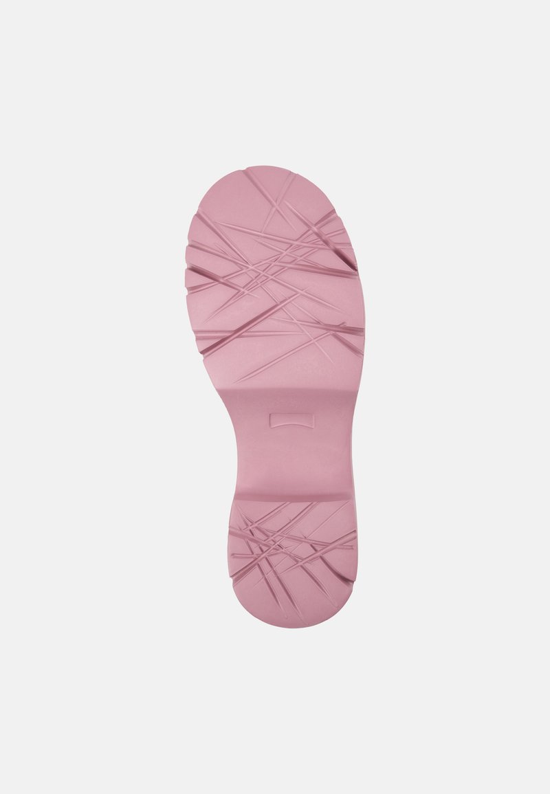 Semelle de chaussure en caoutchouc rose clair, avec un motif texturé comprenant des lignes diagonales et des crêtes pour une meilleure adhérence. Bout arrondi et bords lisses.