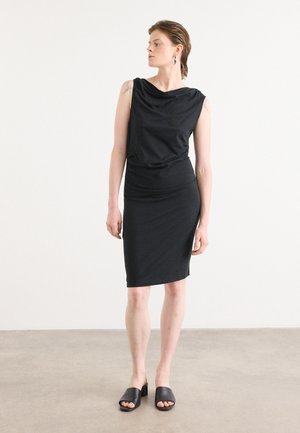Black sleeveless dress with draped neckline, fitted silhouette, and knee-length hem. Worn with black slide sandals. Smooth fabric texture.