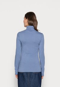 Maglia a maniche lunghe, colletto a imbuto di colore azzurro chiaro, realizzata in materiale morbido, design aderente con una texture liscia, abbinata a una gonna di jeans.
