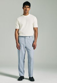 Weißes, strukturiertes Kurzarmhemd, hellblaue, taillierte Hose und schwarze Schuhe. Einfaches Design mit entspannter Passform und funktionalem Bund.