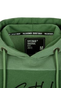 Felpa verde con cappuccio regolabile, tessuto strutturato e occhielli in metallo. Le etichette riportano "SPITZBUB" e "PULLOVERMON" in colori a contrasto.