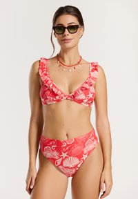 Piros bikini szett fehér kagyló és tengeri mintákkal. Triangel melltartó fodros pántokkal, magas derekú alsórész, sima textúrával.