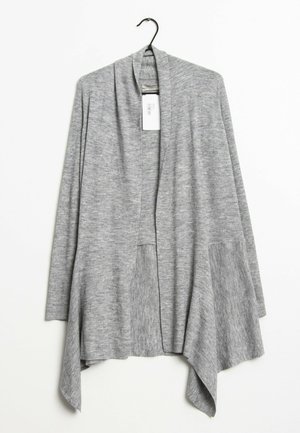 Hellgraue, offene Strickjacke mit langen Ärmeln, zwei Vorderfächern und asymmetrischem Saum, die an einem schwarzen Kleiderbügel hängt.