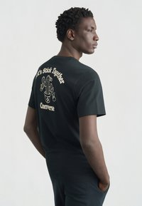 Μαύρο βαμβακερό t-shirt με γραφικό κάκτου και το κείμενο «Ας μείνουμε μαζί» σε ρετρό στυλ στην πλάτη.