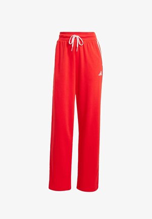 Rote Sweatpants aus weichem Stoff. Mit weit geschnittenen Beinen, elastischem Bund mit Kordelzug und einem weißen Logo am linken Oberschenkel.