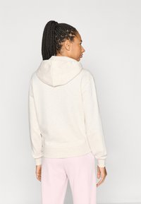 Φόρμα με κουκούλα σε ανοιχτό μπεζ χρώμα με άνετη εφαρμογή, διαθέτει κουκούλα με κορδόνι και ριμπ μανσέτες. Λεπτή υφή με τσέπη τύπου καγκουρό.