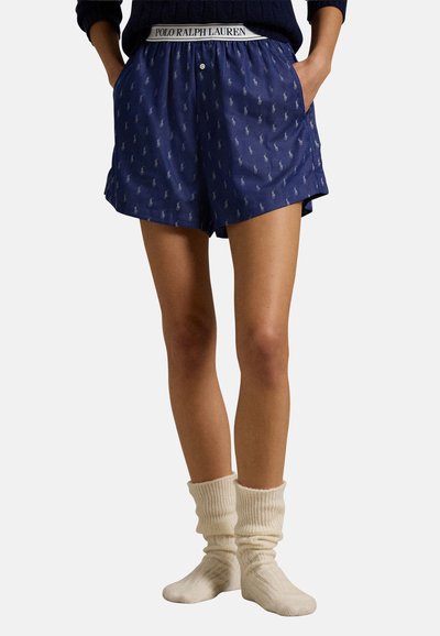 Marineblauwe shorts met witte Polo-logo print, elastische tailleband, zijzakken en een relaxte pasvorm. Gepaard met crèmekleurige ribgebreide kniekousen.